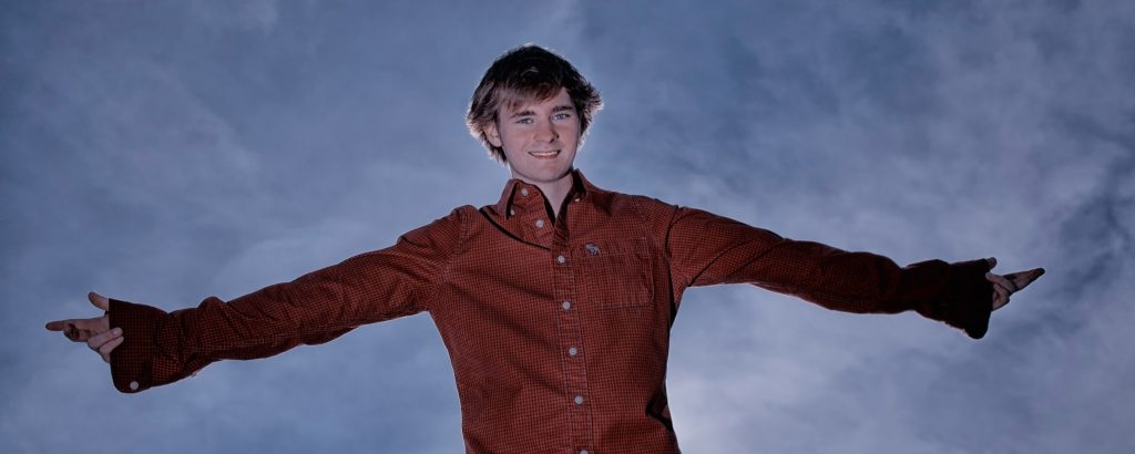 Senior portrait of a guy with a beautiful blue sky created near Brenham, Tx by Sandy Flint