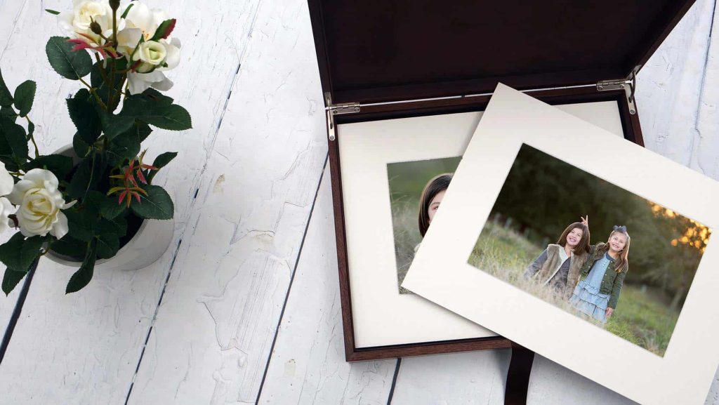A hand-crafted walnut box containing a collection of matted images from a family portrait session.